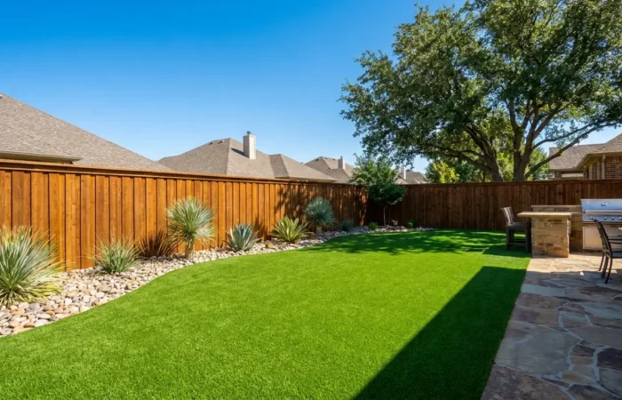 Lush green artificial turf backyard with a stained wood fence in Lubbock, TX, illustrating artificial turf cost