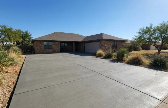 Freshly poured smooth concrete driveway leading to a brick home, illustrating concrete driveway cost in Lubbock, TX